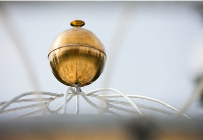 Dekorkugel in Messingfarben auf Pavillon montiert