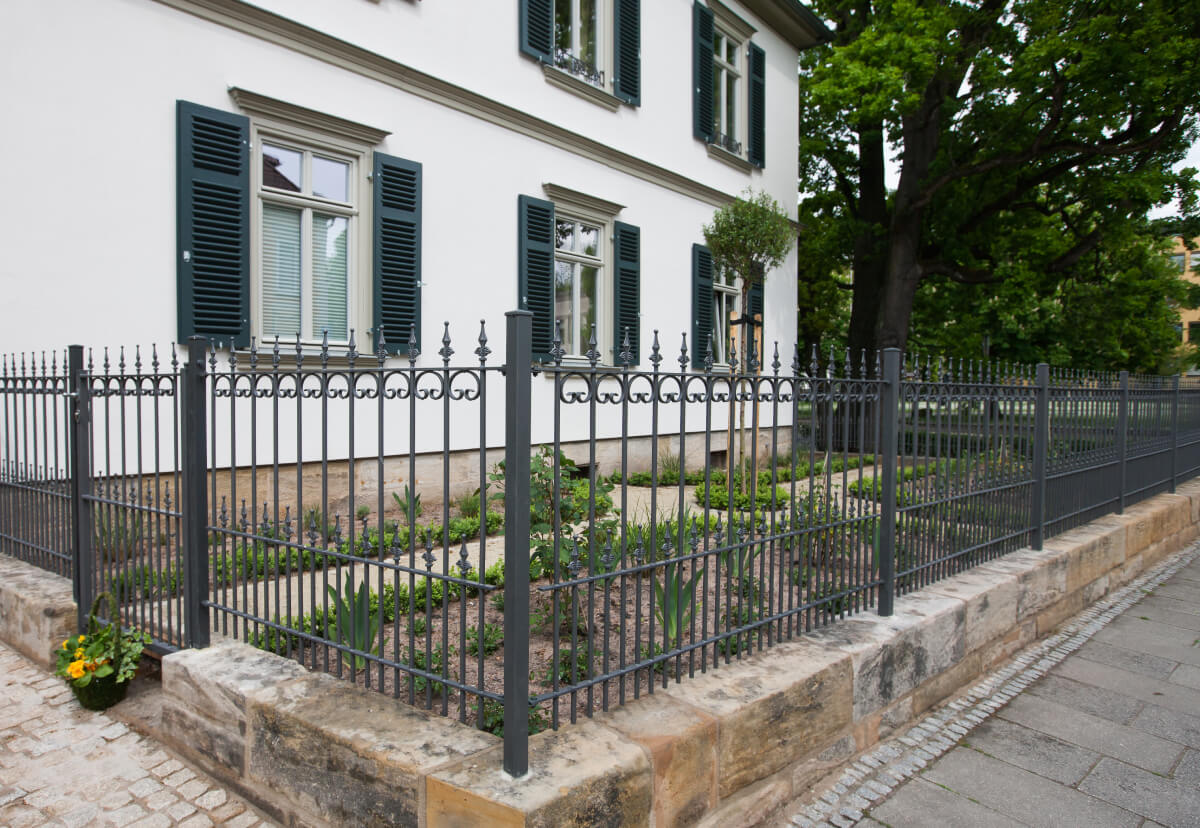 Zaun Lucca vor einem weißen Haus mit bepflanztem Vorgarten | Pulverbeschichtet anthrazit